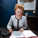 A focused woman working on paperwork in a modern office environment.